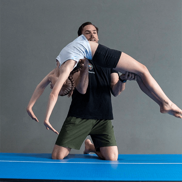 kid doing a back-flip with her coach