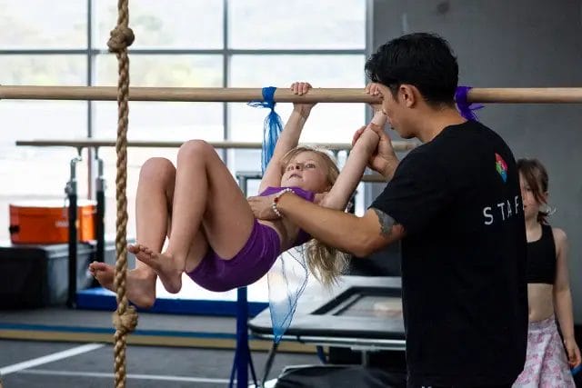 Modbod Gymnastics coach assisting child during gymnastics training